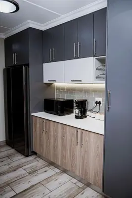 a kitchen with black cabinets and a black refrigerator at Walton Luxe Retreat in Midrand