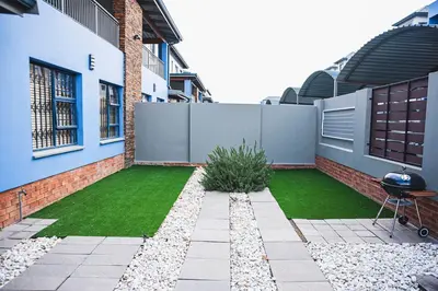 a backyard with a grassy yard next to a building at Walton Luxe Retreat in Midrand