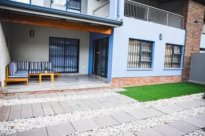 a patio with two benches and a green lawn at Walton Luxe Retreat in Midrand