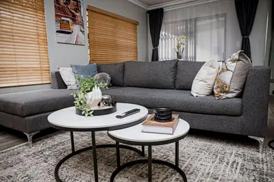 a living room with a gray couch and two tables at Walton Luxe Retreat in Midrand