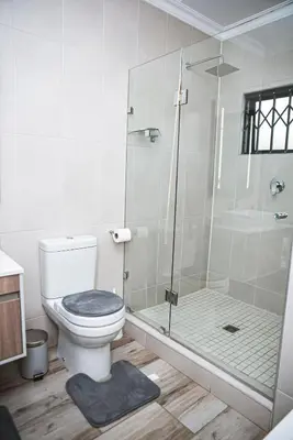 a bathroom with a toilet and a glass shower at Walton Luxe Retreat in Midrand