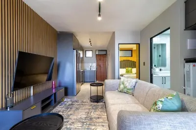 a living room with a couch and a flat screen tv at The Manson's BishopsCourt in Pretoria
