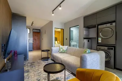 a living room with a couch and a kitchen at The Manson's BishopsCourt in Pretoria