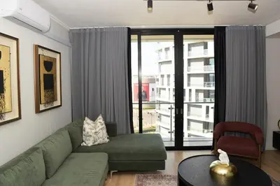 a living room with a green couch and a large window at Ellipse Olive and Vine in Midrand