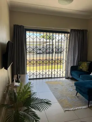 a living room with a blue couch and a glass door at The West End 252 in Midrand