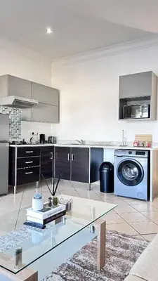 a kitchen with a washing machine and a glass table at Luxury Lakeview Retreat in Pretoria