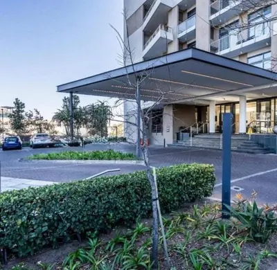 a small tree in a parking lot in front of a building at Modern Studio in Menlyn Maine in Pretoria
