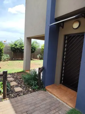 a blue building with a garage door next to a yard at Aspen Creek in Benoni