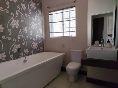 a bathroom with a tub and a toilet and a sink at Aspen Creek in Benoni