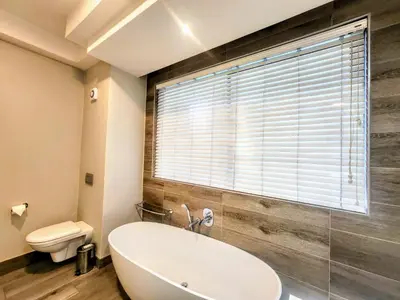 a bathroom with a tub and a toilet and a window at Modern loft at Regency in Pretoria