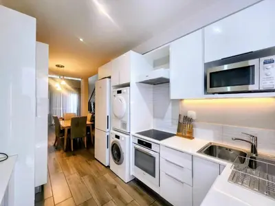 a white kitchen with a washer and dryer at Modern loft at Regency in Pretoria