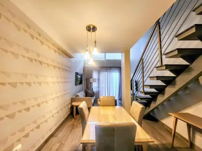 a dining room with a table and a staircase at Modern loft at Regency in Pretoria