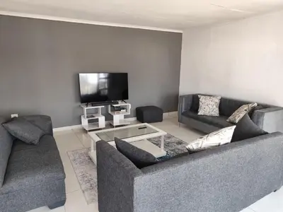 a living room with two couches and a flat screen tv at Doringdraad Lodge Rooms Mufasa and Simba in Brendan Village