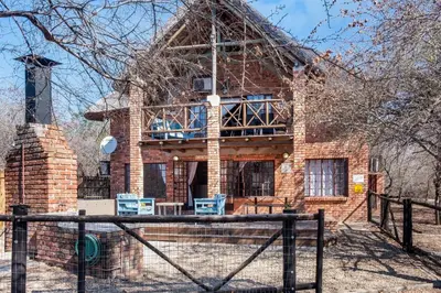 a brick house with a porch and a fence at Timbuktwini, Marloth Park, Mpumalanga in Marloth Park