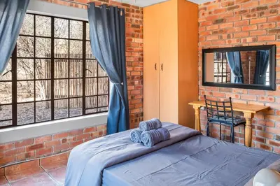 a bedroom with a bed and a brick wall at Timbuktwini, Marloth Park, Mpumalanga in Marloth Park