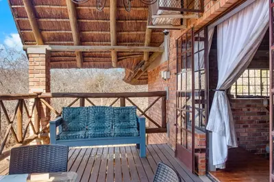 a blue bench sitting on a deck with awning at Timbuktwini, Marloth Park, Mpumalanga in Marloth Park