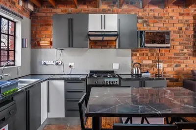 a kitchen with stainless steel appliances and a brick wall at Timbuktwini, Marloth Park, Mpumalanga in Marloth Park