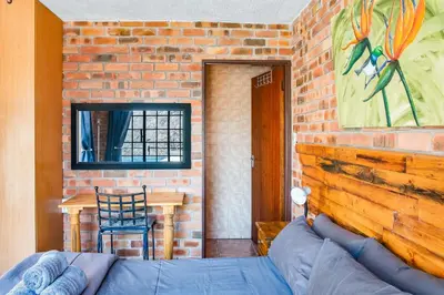 a room with a couch and a brick wall at Timbuktwini, Marloth Park, Mpumalanga in Marloth Park