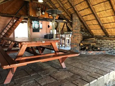 a wooden picnic table in a room with a fireplace at Doringdraad Lodge Nala and Zazu in Brendan Village