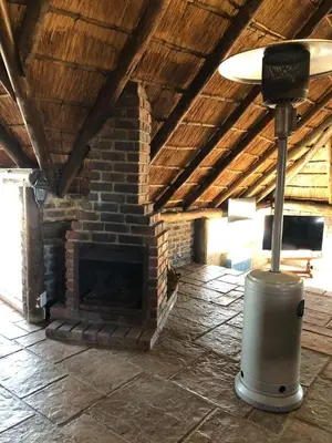 a brick fireplace in a living room with a lamp at Doringdraad Lodge Nala and Zazu in Brendan Village