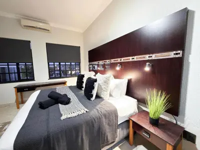 a bedroom with a large bed with a wooden headboard at Promenade Place Nelspruit in Nelspruit