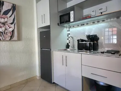 a kitchen with white cabinets and a microwave at Promenade Place Nelspruit in Nelspruit