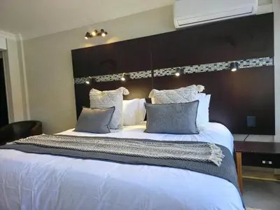 a large bed with blue pillows in a bedroom at Promenade Place Nelspruit in Nelspruit