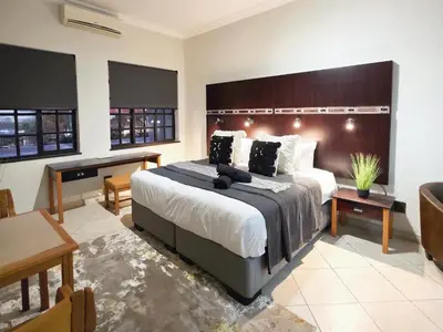 a large bedroom with a large bed and a desk at Promenade Place Nelspruit in Nelspruit