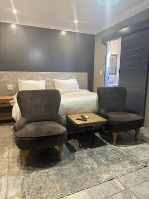 a bedroom with a bed and two chairs and a table at Yinjwasi Hill guest house in Armburg