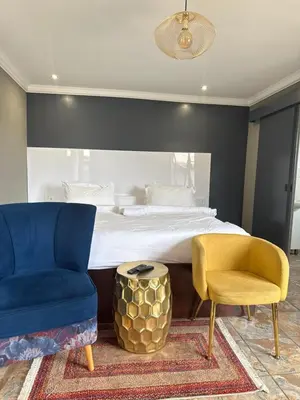 a bedroom with a bed with a blue chair and a yellow chair at Yinjwasi Hill guest house in Armburg