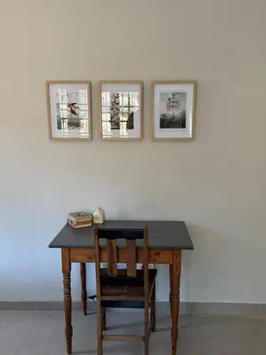 a table with a chair and three pictures on a wall at Around the corner in Pretoria