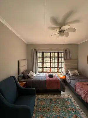 a bedroom with two beds and a ceiling fan at Around the corner in Pretoria