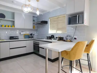a kitchen with white cabinets and a table and chairs at Wapadrand Modern Self-catering Apartment in Pretoria