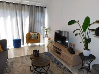 a living room with a flat screen tv and a couch at Wapadrand Modern Self-catering Apartment in Pretoria