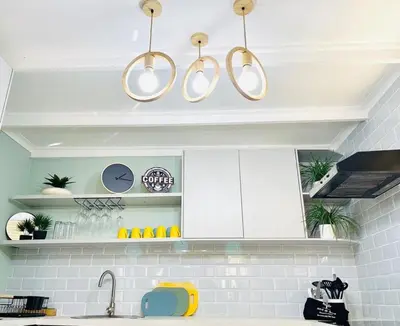 a kitchen with white cabinets and gold pendant lights at Wapadrand Modern Self-catering Apartment in Pretoria