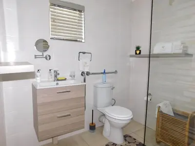 a white bathroom with a toilet and a sink at Wapadrand Modern Self-catering Apartment in Pretoria