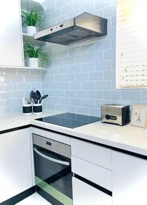 a kitchen with white cabinets and blue tiles at Wapadrand Modern Self-catering Apartment in Pretoria
