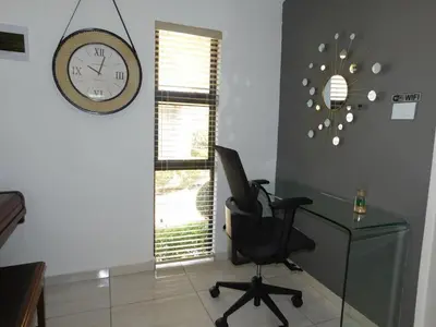 a office with a desk and a chair and a clock at Wapadrand Modern Self-catering Apartment in Pretoria