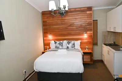 a bedroom with a large bed with a wooden headboard at Morning Star Guest House in Kempton Park