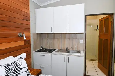 a small kitchen with white cabinets and a sink at Morning Star Guest House in Kempton Park