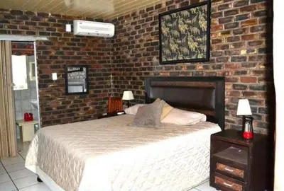 a bedroom with a bed and a brick wall at Martys Place in Marloth Park