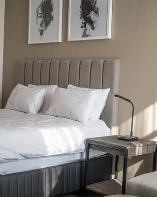 a bed with white pillows and a table with a lamp at Menlyn Maine Trilogy Apartment in Pretoria
