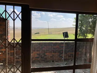 a window with a view of a field seen through it at Doringdraad Lodge Room Rafiki in Brendan Village