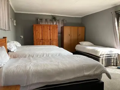 a bedroom with two beds and wooden cabinets at Doringdraad Lodge Room Rafiki in Brendan Village