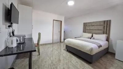 a bedroom with a bed and a desk with a television at 7th Heaven Boutique Hotels in Burgersfort