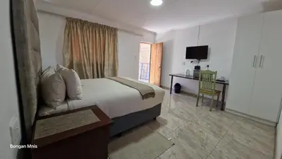 a bedroom with a bed and a desk and a television at 7th Heaven Boutique Hotels in Burgersfort