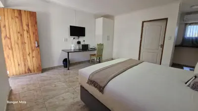 a bedroom with a bed and a desk with a computer at 7th Heaven Boutique Hotels in Burgersfort