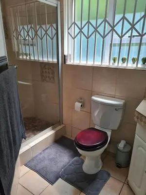 a bathroom with a shower and a toilet with a red seat at Villa at 185 Milner Street in Pretoria
