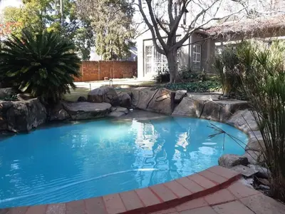 a swimming pool with a rock retaining wall in a yard at Villa at 185 Milner Street in Pretoria