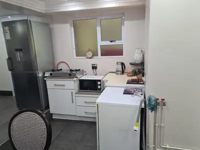 a small kitchen with a refrigerator and a sink at Villa at 185 Milner Street in Pretoria